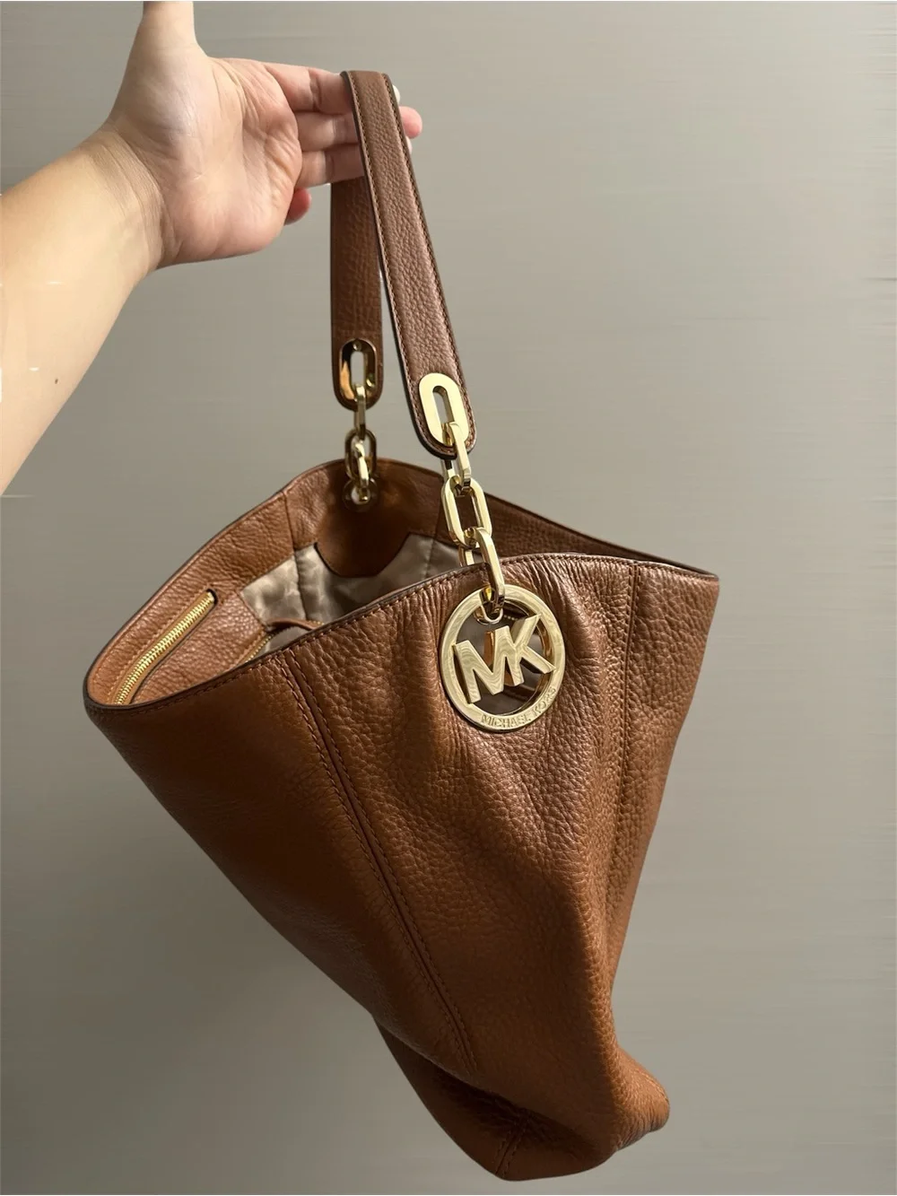 Michael Kors Cognac Pebbled Leather Shoulder Bag with Gold logo on the side.